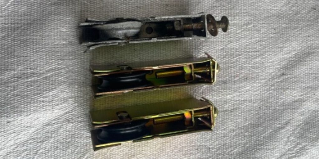 Worn sliding door roller with a flat, cracked wheel
